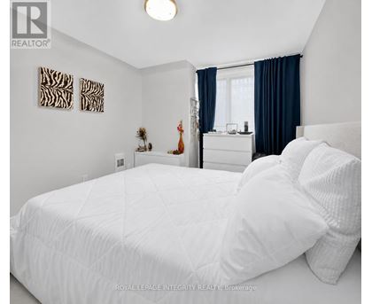 A bedroom with a white bed and a window with blue curtains.