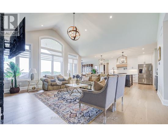 A well-lit, spacious living room with a grey sofa set and a large rug.