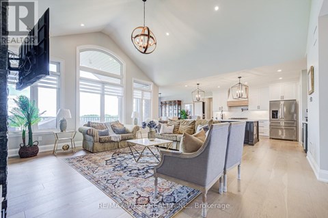 A well-lit, spacious living room with a grey sofa set and a large rug.