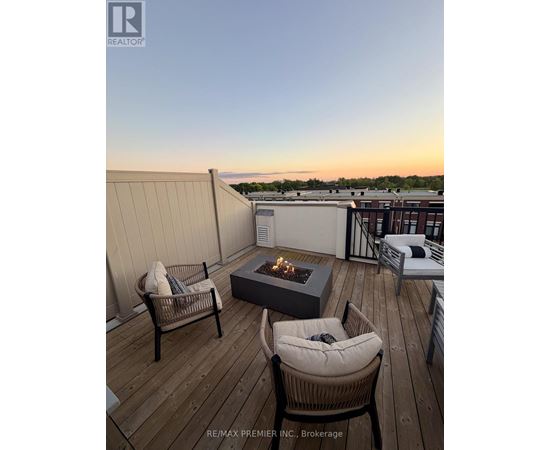 A wooden deck with a fire pit and chairs.