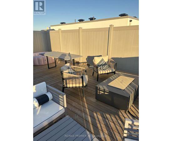 A sunny outdoor patio with a white couch, chairs, and a table.