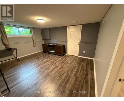 A room with a wooden floor and a window with curtains.