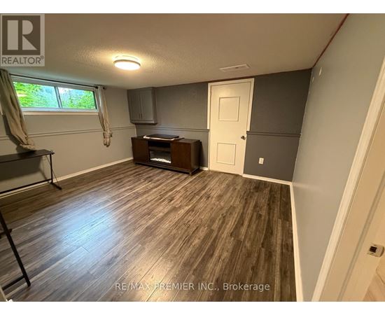A room with a wooden floor and a window with curtains.