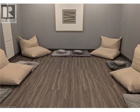 A room with a grey wall and a wooden floor with a rug and four pillows.
