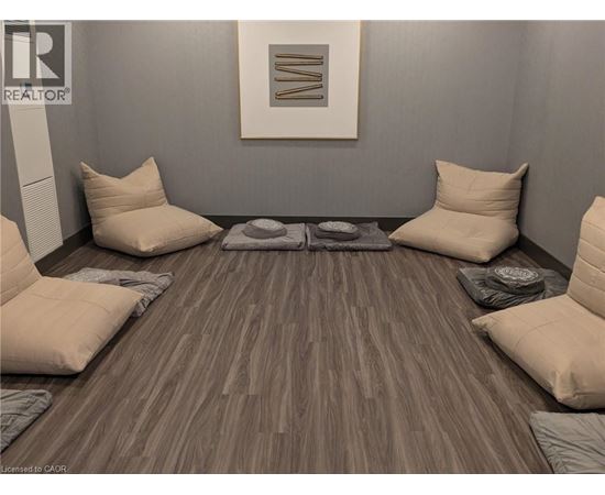 A room with a grey wall and a wooden floor with a rug and four pillows.