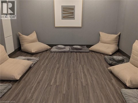 A room with a grey wall and a wooden floor with a rug and four pillows.