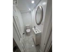 A white bathroom with a toilet, sink and mirror.