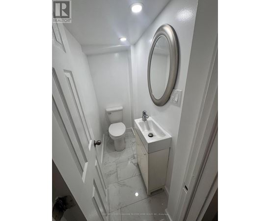 A white bathroom with a toilet, sink and mirror.