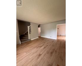 A room with wooden flooring and a staircase leading to another room.