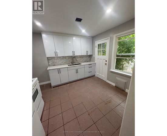 A kitchen with white cabinets and a tiled floor.