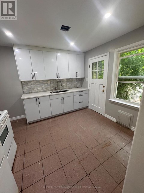 A kitchen with white cabinets and a tiled floor.