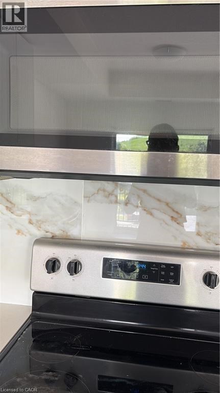 A modern kitchen with a stove top oven and a marble backsplash.