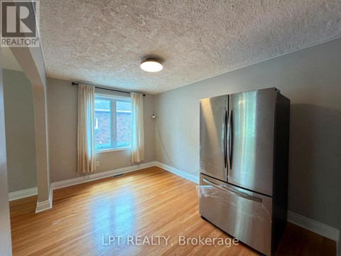 A kitchen with a stainless steel refrigerator and wooden flooring.
