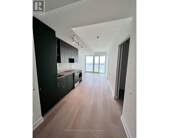 A spacious kitchen with black cabinets and a wooden floor.