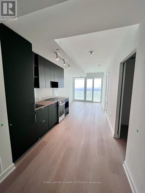 A spacious kitchen with black cabinets and a wooden floor.
