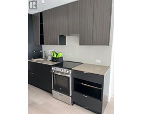 A modern kitchen with a black oven and a grey backsplash.