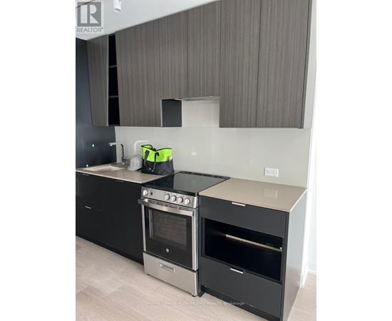 A modern kitchen with a black oven and a grey backsplash.