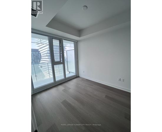 A room with a sliding glass door and wooden flooring.