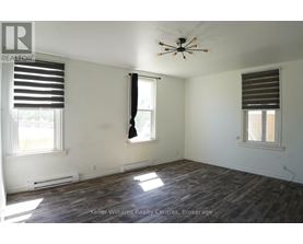 A room with a ceiling fan and two windows.