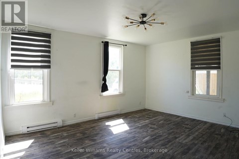 A room with a ceiling fan and two windows.