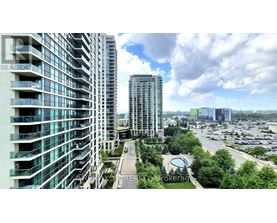 A view of a cityscape with a large building in the foreground and a parking lot in the background.