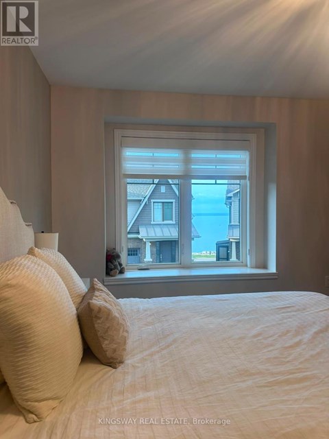 A bedroom with a large bed and a window overlooking a house.