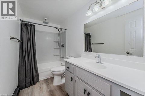 A white bathroom with a toilet, sink, and shower.