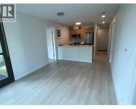 A spacious living room with a kitchen area in the background.