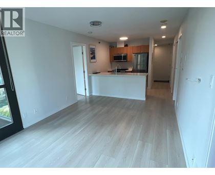 A spacious living room with a kitchen area in the background.