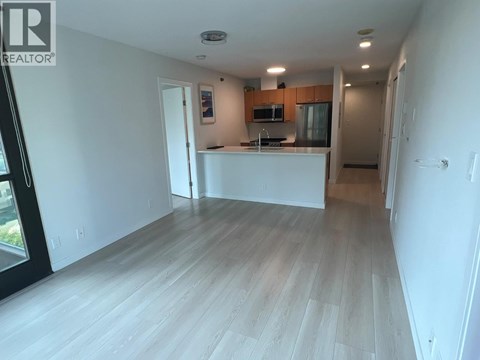 A spacious living room with a kitchen area in the background.