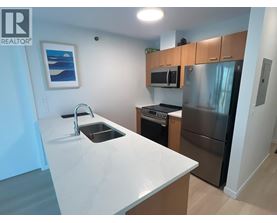 A kitchen with a white counter top and stainless steel appliances.