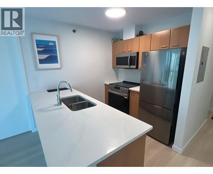A kitchen with a white counter top and stainless steel appliances.
