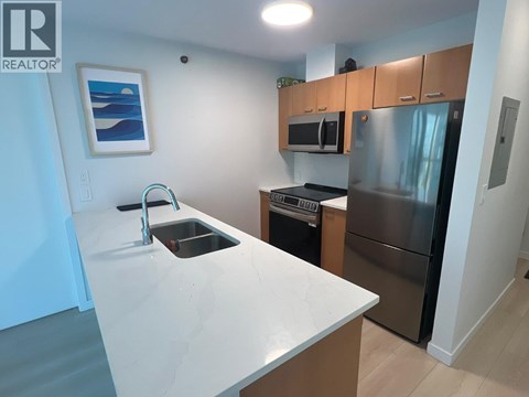 A kitchen with a white counter top and stainless steel appliances.
