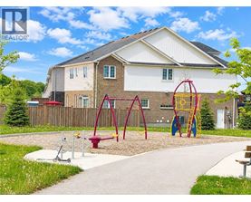 A playground with a swing set and a slide in front of a house.