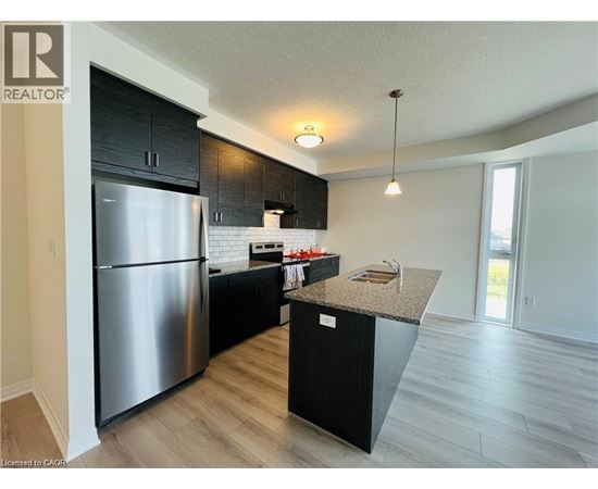 A modern kitchen with a stainless steel refrigerator and black cabinets.