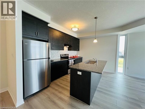A modern kitchen with a stainless steel refrigerator and black cabinets.