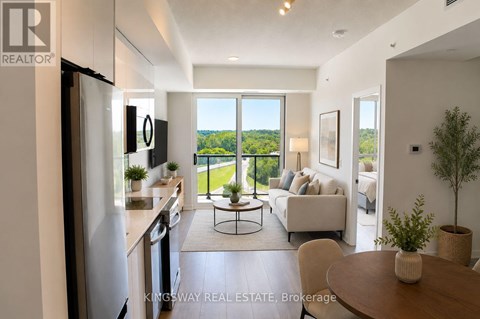 A well-lit, modern kitchen with a dining table and chairs in the foreground and a balcony with a view of trees in the background.