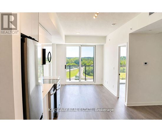A kitchen with a refrigerator, sink, and a view of the backyard through a sliding glass door.