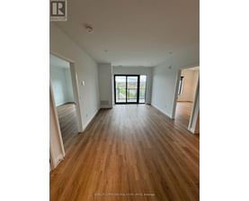 A spacious room with wooden flooring and a view of a balcony through a glass door.