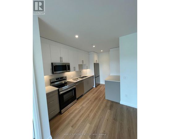 A modern kitchen with wooden floors and stainless steel appliances.
