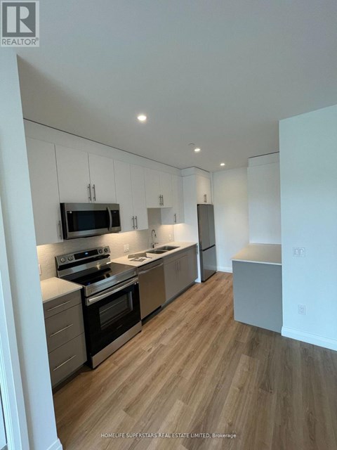 A modern kitchen with wooden floors and stainless steel appliances.