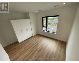 A room with wooden flooring and a large window overlooking a parking lot.