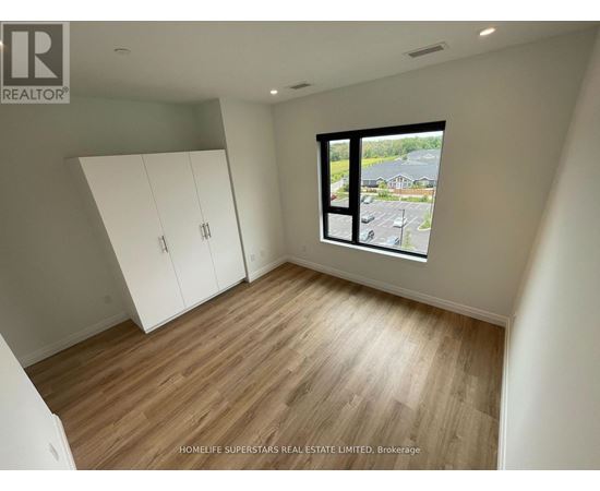 A room with wooden flooring and a large window overlooking a parking lot.
