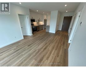 A spacious living room with wooden flooring and white walls.