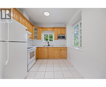 A kitchen with white appliances and wooden cabinets.