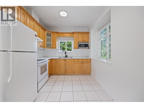 A kitchen with white appliances and wooden cabinets.