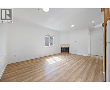 A spacious room with wooden flooring and white walls.