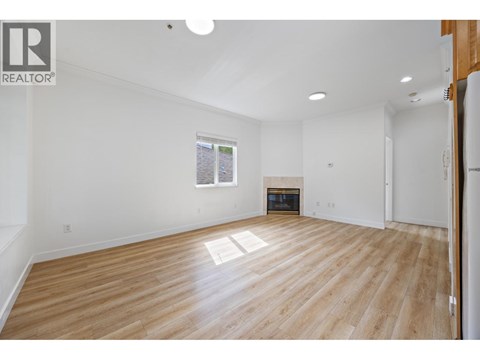 A spacious room with wooden flooring and white walls.