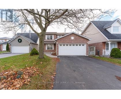 A residential house with a driveway and a tree in front.