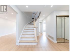 A spacious room with a wooden staircase and white walls.